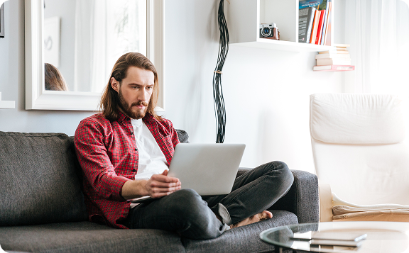 serious-man-sitting-using-laptop-sofa-home