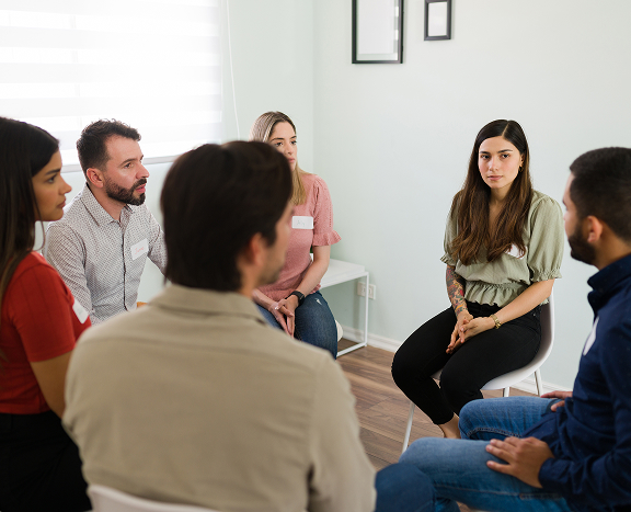 young-man-communicating-with-participants-group-therapy-community-center CBT Therapy